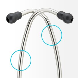 Branches en aluminium brillant d’un stéthoscope 3M Littmann se croisant symétriquement avec des embouts auriculaires noirs à l’extrémité. 