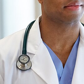 Stéthoscope Littmann porté de manière appropriée par-dessus le col d’une blouse blanche pour éviter que la tubulure ne touche le cou du médecin.